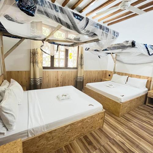 two bunk beds in a room with wooden floors at Ondo House in Nungwi