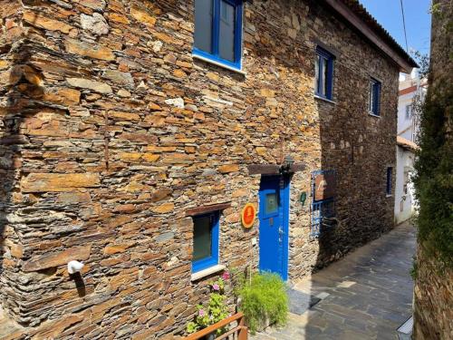 a stone building with a blue door on a street at Campus Natura in Arganil