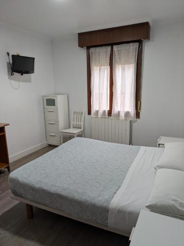 a bedroom with a large bed and a window at Akelarre Ostatua in Guernica y Luno
