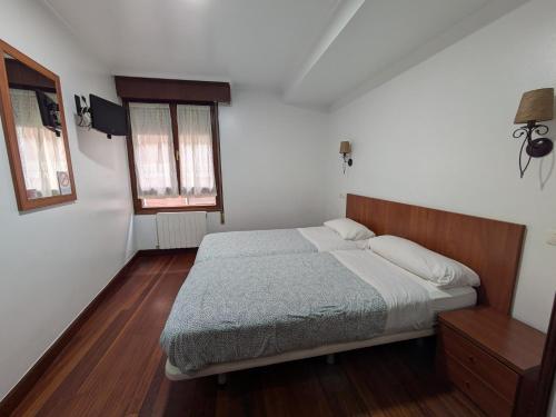 a bedroom with a large bed and two windows at Akelarre Ostatua in Guernica y Luno