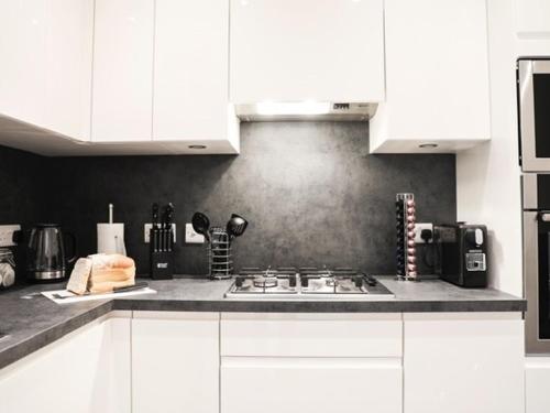 a kitchen with white cabinets and a stove top oven at Casa Fresa - King Street Apartments in Dundee
