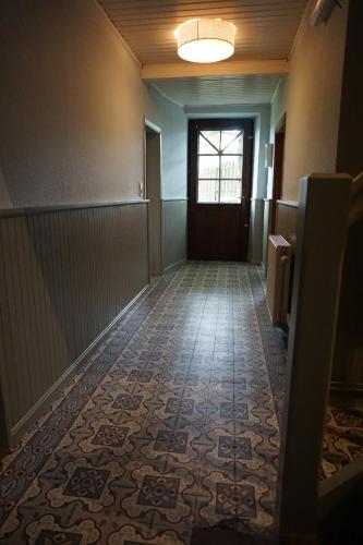 een lege gang met een deur en een tegelvloer bij Maison Matan in Houdremont