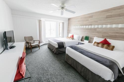 a hotel room with two beds and a flat screen tv at Elk + Avenue Hotel in Banff