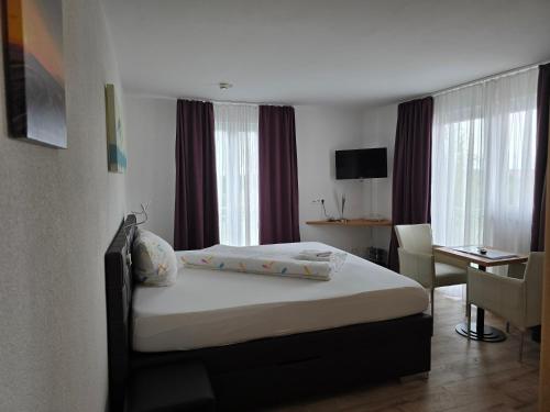 a hotel room with a bed and a desk and a room at Hotel Ackermann in Riedstadt