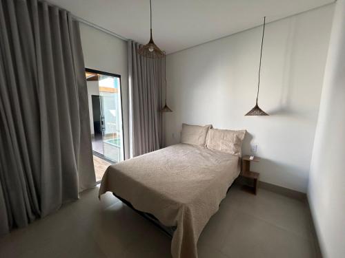 a white bedroom with a bed and a window at Casa Green Ville in Prado