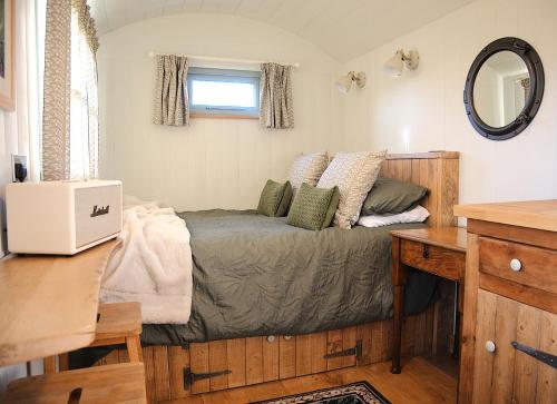 a small bedroom with a bed and a desk at Seaside Shepherd's Hut in Mundesley