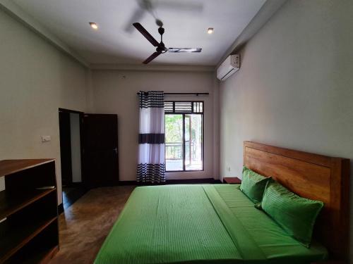 a bedroom with a green bed and a window at Lake view Oasis Koggala in Malalagamaduwa