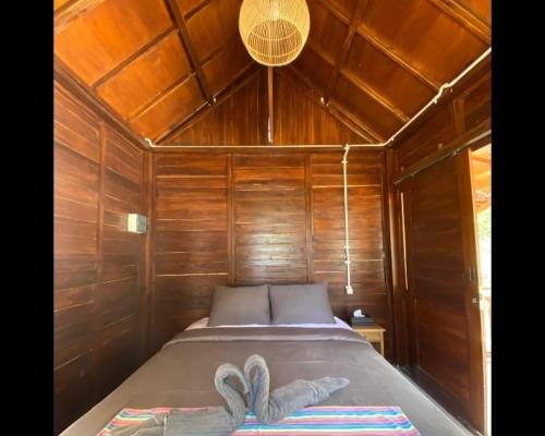 a bed in a wooden cabin with two towels on it at Kahurangi Hotel in Sekongkang