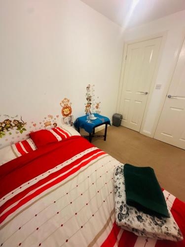a bedroom with a red and white bed with a blue table at Stay with LL in Doncaster