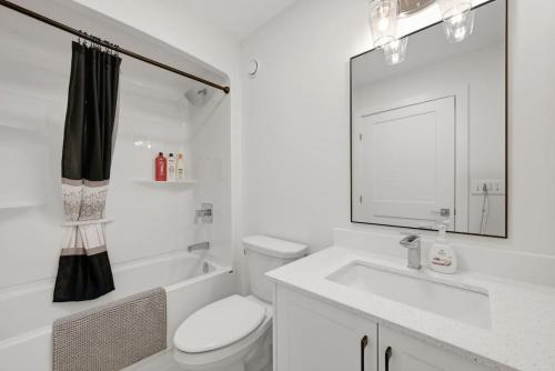 a white bathroom with a sink and a toilet and a tub at Quiet and Convenient Retreat in Hammonds Plains