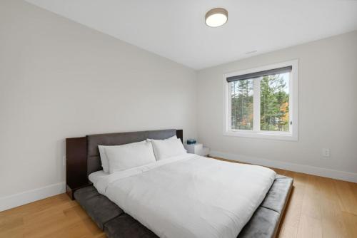 a white bedroom with a large bed and a window at Quiet and Convenient Retreat in Hammonds Plains