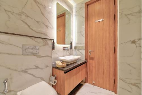 ein Badezimmer mit Waschbecken, Toilette und Spiegel in der Unterkunft Dwellr Luxury Stays - Golf Course Road in Gurgaon