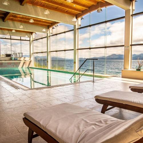 a room with a pool and a bed and windows at Alma Del Lago Suites & Spa in San Carlos de Bariloche