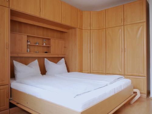 a bedroom with a large white bed with wooden cabinets at Seegurke in Am Schwarzen Busch