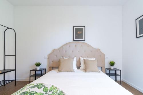 a bedroom with a large white bed with two tables at Jouvacations Villa Osona in Vilafant