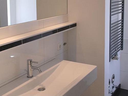 a white bathroom with a sink and a mirror at Burg Roland Wohnung 06 in Dierhagen