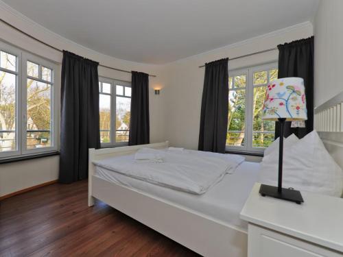 a bedroom with a large white bed and windows at Burg Roland Wohnung 06 in Dierhagen
