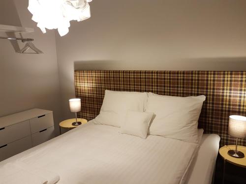 a bedroom with a white bed with two lamps at CCH Elephant Apartments in Poznań
