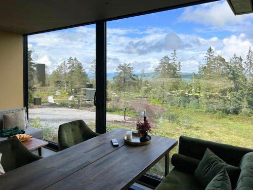 a living room with a wooden table and a large window at Modern Cabin At Blefjell in Svene