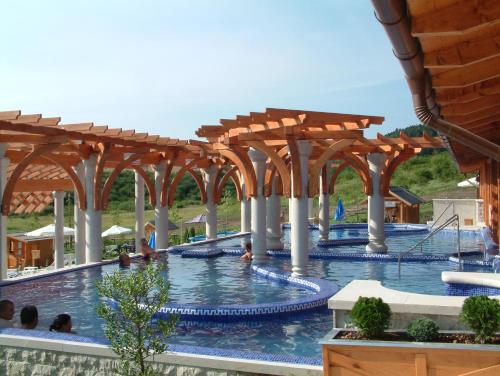 a pool at a resort with wooden arbors at Sas-Fészek Vendégház in Demjén