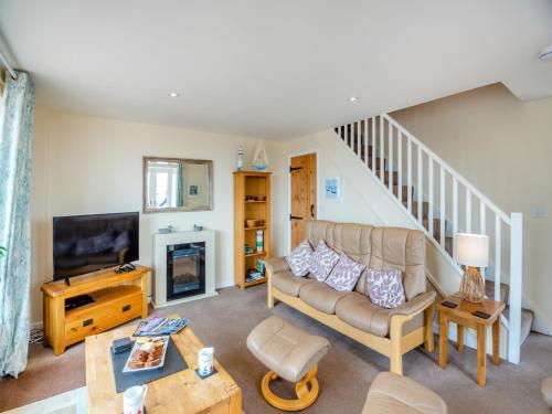 a living room with a couch and a tv at Golygfa Hudol - Uk46712 in Pwllheli