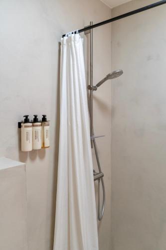 eine Dusche mit weißem Duschvorhang in einem Badezimmer in der Unterkunft Strandhotel Klitrosen in Fjerritslev
