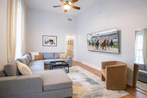 a living room with a couch and a horse race picture on the wall at Remodeled Modern Home - private backyard & games! in Louisville