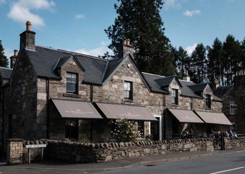 an old stone building with black roofs on a street at The Grandtully Hotel in Grandtully