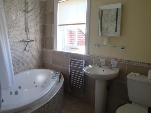 a bathroom with a bath tub and a sink at Anglesey Hotel in Gosport