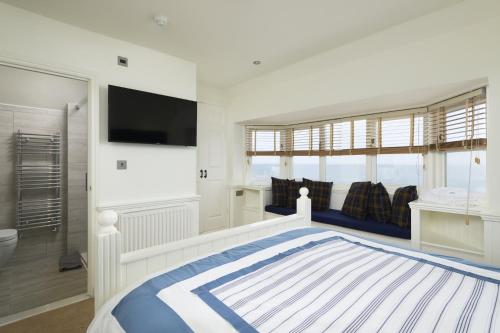 a white bedroom with a large bed and a flat screen tv at The Cricket Inn in Kingsbridge