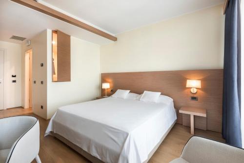 a bedroom with a large white bed and two chairs at Il Porticciolo in Laveno-Mombello