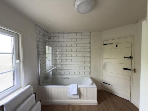 a white bathroom with a tub and a window at 2 Aqueduct Cottages in Wrexham