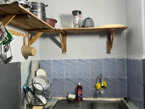 una cucina con un lavandino e ripiani in legno sopra di esso di Beni'o Suite a Adiapo-Doumé