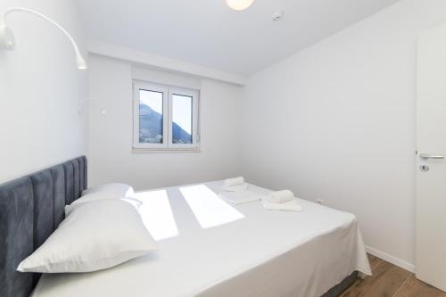 a white bedroom with a bed and a window at Inamore in Gradac