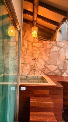 a bathroom with a shower and a stone wall at Villa Triacca Hotel Vinícola & Spa in Brasília
