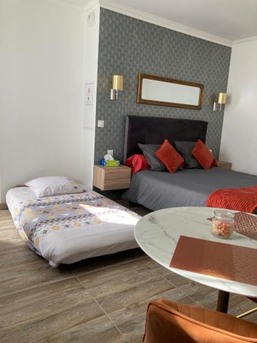 a bedroom with two beds and a table in it at Studio Vintage avec cheminée décorative in Villefranche-sur-Saône