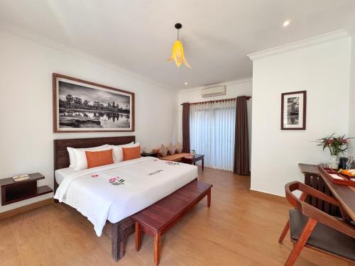 a bedroom with a large bed and a desk at Emerald Angkor Siem Reap in Siem Reap