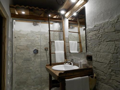 uma casa de banho com um lavatório e um chuveiro com um espelho. em B&B Le Ciaf em Temù