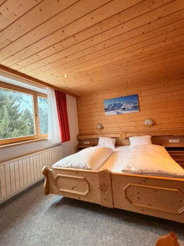 a bed in a room with a wooden ceiling at Damülser Horn in Damuls