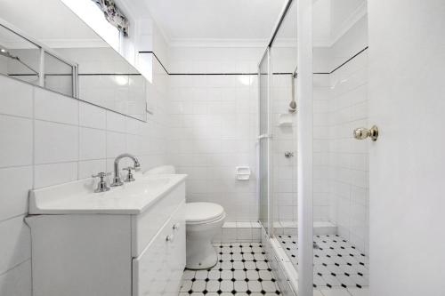 a white bathroom with a sink and a toilet at Moonya Courtyard in Carnegie