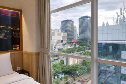 a bedroom with a window with a view of a city at Smart Hotel Thamrin Jakarta in Jakarta