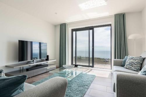 a living room with a television and a glass table at Beachcliff - On the Seafront with Two Balconies in Bournemouth