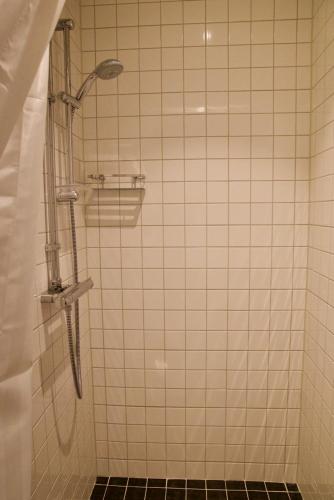 a shower in a bathroom with a tiled wall at KSSS Vandrarhem Telegrafholmen in Sandhamn