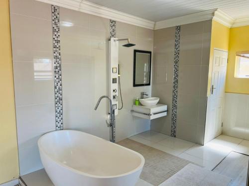 a white bathroom with a tub and a sink at Umsobomvu Guest House in Mthatha