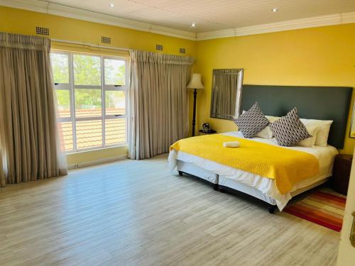 a bedroom with a large bed with a yellow blanket at Umsobomvu Guest House in Mthatha