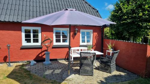 a red house with a table and an umbrella at Stouwhuset Øster Hurup in Hadsund