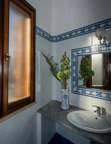 a bathroom with a sink and a vase with flowers at Hotel Sirio in Lampedusa