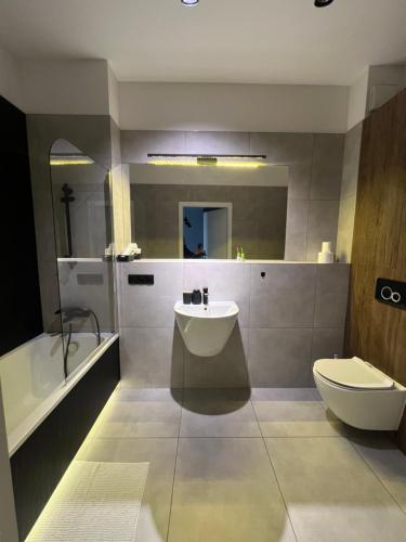 a bathroom with a sink and a toilet and a tub at Apartament Augustynika in Dąbrowa Górnicza