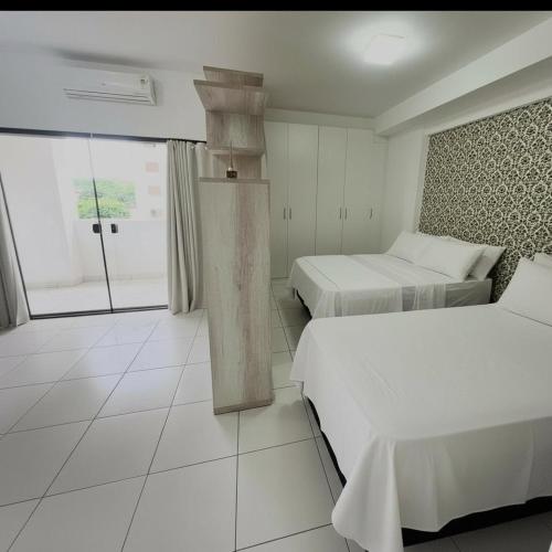 a hotel room with two beds and a window at Santorini Piscina Hidro Academia Salt Hospital Premium Jaime Câmara Mercatto Store Moreira Marista Blue Fit Perdomo Vaca Brava Goiânia Shopping Areião Marista Ze Abílio Serrinha Campo do Goiás Hailé Pinheiro in Goiânia