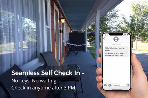 a person holding a cell phone in front of a house at Highbrook Motel in Bar Harbor
